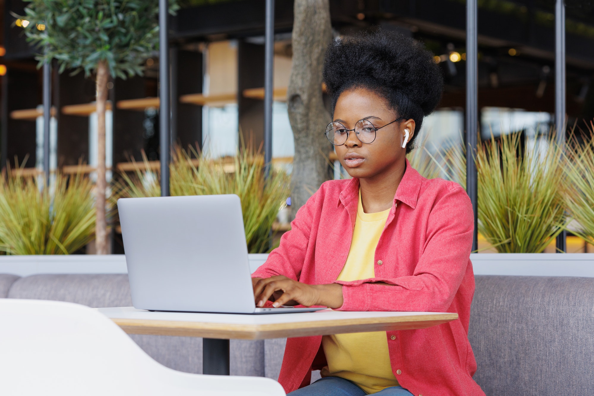 African American woman works on a laptop in a coworking or office, watches a training webinar